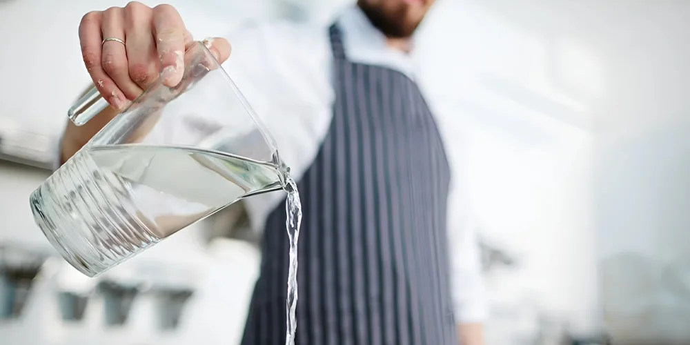 A man is pouring a glass of water.