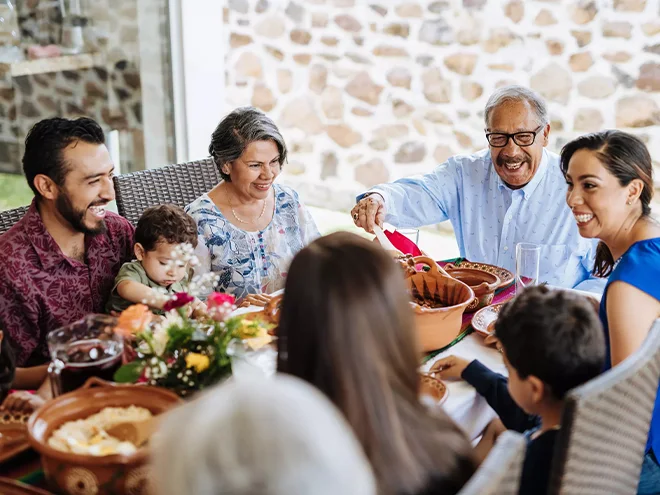 Many people are smiling and talking at the dining table.