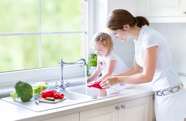 Una madre y su hija están lavando verduras.