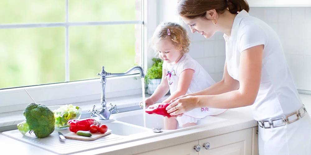 A mother and a daughter are washing vegetables.