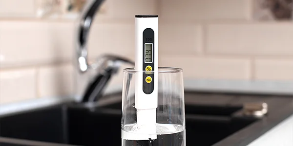 Un medidor de TDS se coloca en una taza de agua.