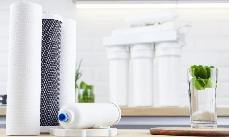 A glass of water and several filter cartridges of different models are placed on the table.