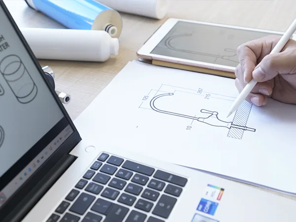 A person is drafting a faucet design drawing at a desk.