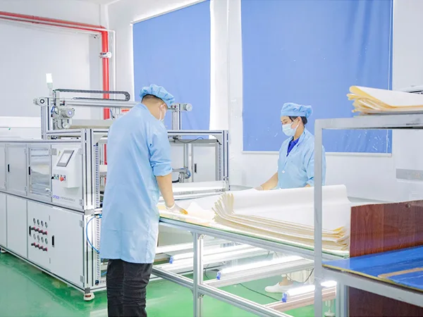 2 workers are handling RO membranes in front of the machine.