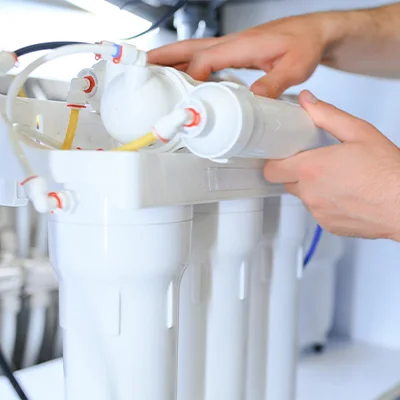 W worker is installing a water purifier filter cartridge.