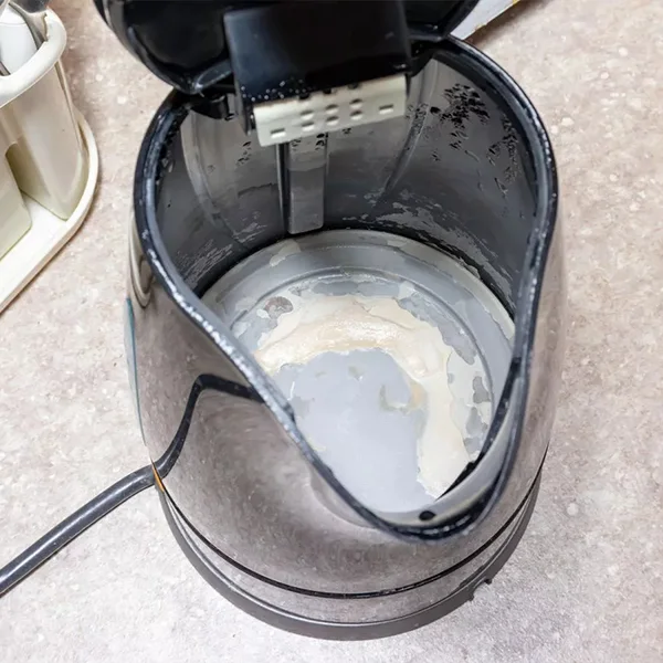 A kettle covered with scale on a table