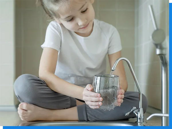 A little girl sits by the pool, filling a water cup.