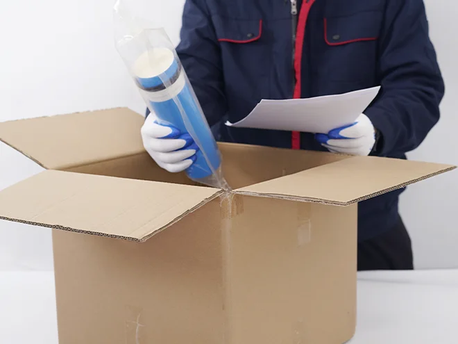 A worker holds a filter cartridge and inspection documents.